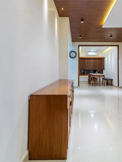 The long wooden sideboard provides a strong horizontal line, creating a sense of contrast with the verticality of the open corridor.