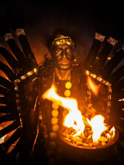 A performer at Kulasai holds a bowl of fire, his face illuminated by the flames. This portrait is a study in light, shadow, and the intensity of ritual performance.