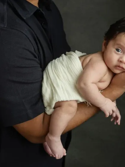 The color close-up, showing the baby's alert expression as she is held securely by her dad.