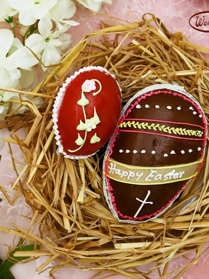 Two of our intricately decorated Marzipan Easter Eggs, nestled in a straw nest. The detailed piping work on each egg is done by hand by our skilled bakers, a tradition we have carried on for many years.