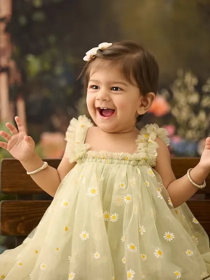 A burst of happy energy. This photo, taken against a lush garden backdrop, perfectly captures the joyful spirit of this little girl.