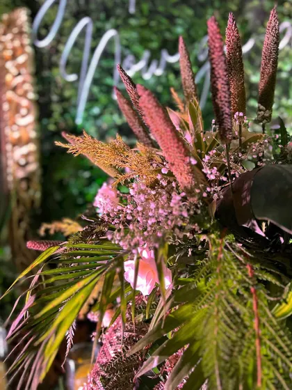 A close-up of a floral arrangement from the whimsical theme, featuring pampas grass and other dried elements mixed with fresh greens.
