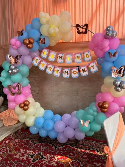 A pastel-themed naming ceremony with a circular balloon frame and a "Naming Ceremony" banner.