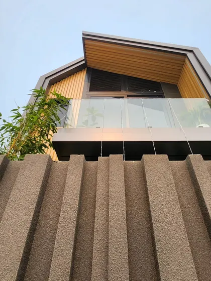 The finished container structure, now a modern studio or home. The exterior is clad with wood and features a glass balcony, completely transforming its original appearance.