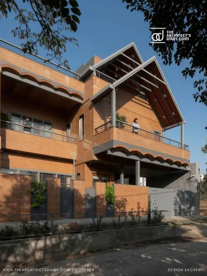 Another perspective of the Madhura residence, showing the interplay of the dual sloping roofs and the warm texture of the exposed brick walls. The design provides each of the two homes with private balconies and terraces.