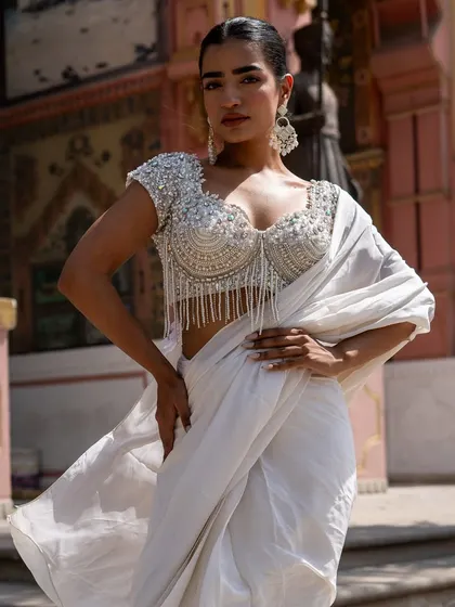 Drench yourself in the pure elegance of our Ivory Edit. This pre-draped saree with a pearl and crystal tassel blouse is a masterpiece of craftsmanship.