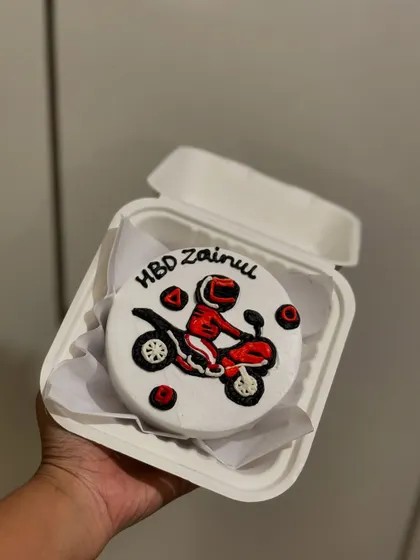 A cool, custom-designed bento cake for a biker's birthday. The cake features a detailed illustration of a person on a dirt bike, perfect for any motorcycle enthusiast.