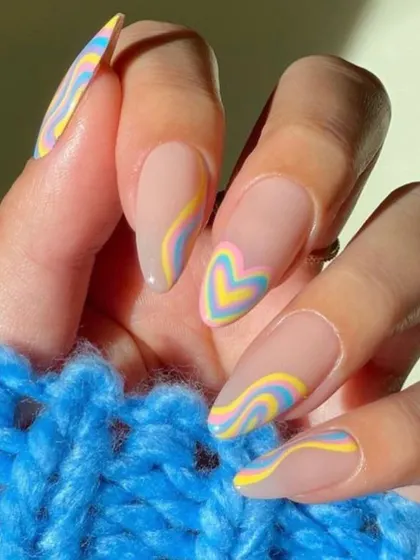 This dreamy, pastel manicure features groovy swirls and a heart-shaped accent nail in shades of yellow, blue, and pink. It's a soft and playful design that's perfect for a whimsical look.