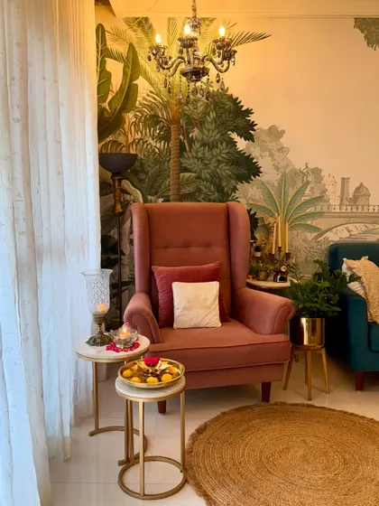 My living room, wrapped in evening calm. This cozy corner with the pink wingback chair, set against the beautiful wallpaper, is my perfect spot to relax after a long day.