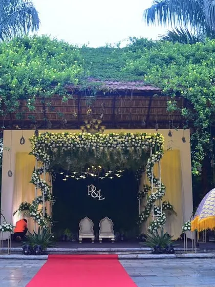 A unique wedding stage setup with traditional umbrellas and a backdrop of lush greenery. This is perfect for a daytime outdoor wedding.