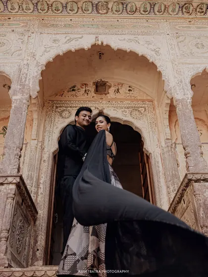 The bride's flowing lehenga creates a beautiful motion as she and the groom pose in front of an ornate doorway at Fort Barwara.