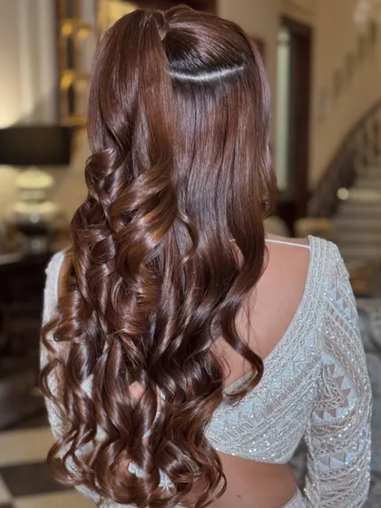 A chic half-ponytail with a clean parting and voluminous curls.