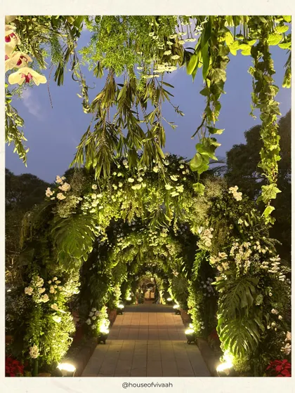 An ethereal floral archway creates a magical entrance path for a wedding in the hills of Mahabaleshwar. The design uses lush foliage and white blooms to craft an immersive, nature-inspired experience.