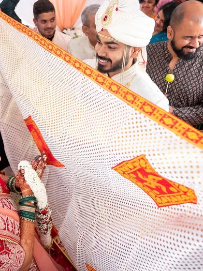 A key moment in a Gujarati wedding, the 'Antarpat' cloth is lowered, and the couple sees each other for the first time at the mandap.