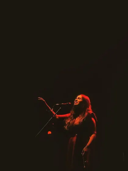 A single red light illuminates the stage during the 'Vari' album release concert. The mood and lighting are so important for setting the emotional tone of the music.
