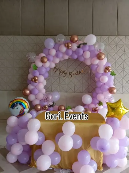 A simple yet charming unicorn-themed table decoration. This setup includes a small balloon arch in pastel purple and pink over a gold-covered table, perfect for a cake-cutting ceremony.