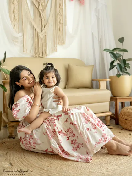 A mother and daughter sit on the floor in a beautifully decorated studio. The daughter's sweet smile makes this a charming and elegant portrait.