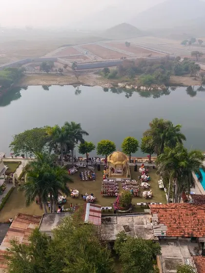 A drone's eye view of the lakeside wedding at Shikarbadi Hotel, capturing the entire layout, from the palace building to the mandap by the water's edge.