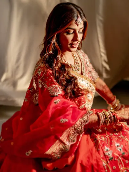 A soft and dreamy bridal look, captured in the warm glow of sunlight. The makeup is subtle yet royal, with a focus on radiant skin and softly defined features.