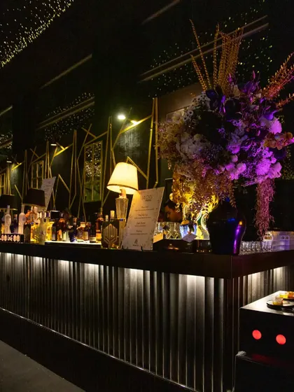 The bar area, styled with a massive floral arrangement in the black, white, and gold palette. Even functional areas of an event are transformed into design statements, ensuring a completely immersive experience.