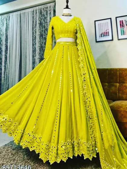 This lightweight georgette lehenga in a stunning lime yellow is perfect for a sangeet or daytime event. The entire outfit is adorned with mirror work and comes with a full-sleeve blouse and a delicate dupatta, offering a bright and glamorous look.