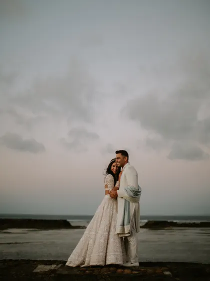 A beautiful shot of the couple against the Bali seascape. The intricate details of her Manish Malhotra lehenga and the subtle elegance of his Anita Dongre sherwani are on full display.