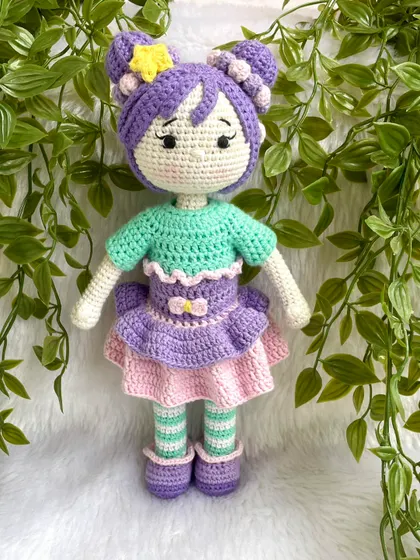 A beautiful doll with purple hair buns and a tutu dress. She also comes with a tiny backpack for her adventures. The striped stockings are attached, but her dress and shoes are removable.