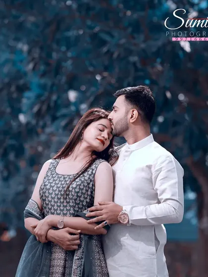 A serene pre-wedding portrait with a cool, blue-toned edit. The groom's gentle kiss on her forehead and their embrace convey a sense of peace and deep affection.