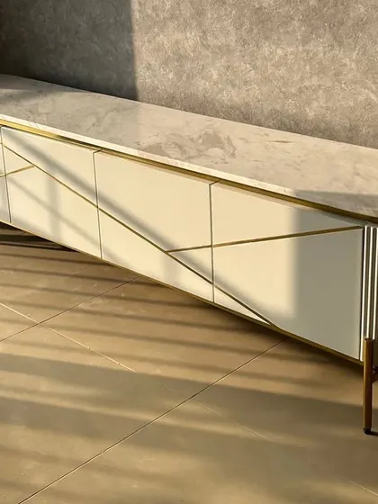 A custom TV unit inspired by our Inlay Console design. This piece features a marble top and a unique geometric pattern on the doors, with a mix of fluted and smooth textures.