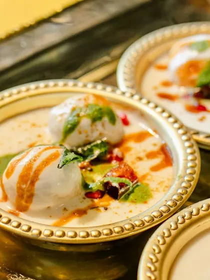 A close-up of the Dahi Vada from our Jain thaali, perfectly soft and soaked in creamy yogurt, garnished with sweet and spicy chutneys.