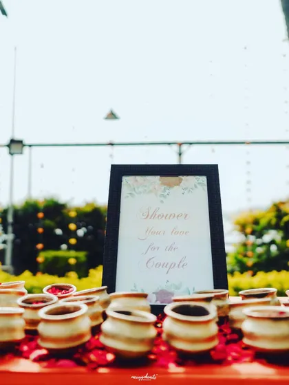 A simple, elegant sign inviting guests to "Shower your love for the couple" with petals.