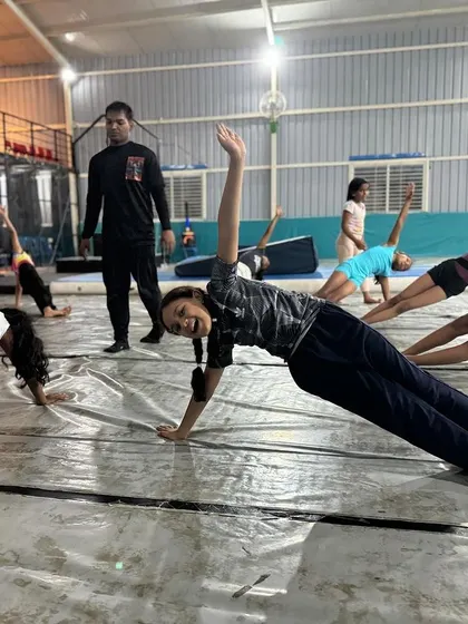 A coach leads a group of smiling students in a side plank hold. We make conditioning engaging and positive for everyone.