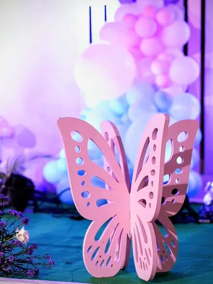 A detailed shot of a 3D butterfly prop against a backdrop of blue and purple balloons, highlighting the small, artistic elements of the party decor.