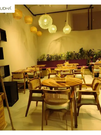 This is a view of a cafe interior I designed. The combination of natural wood furniture, rattan chairs, and clusters of hanging woven lamps creates a warm, earthy, and inviting experience for diners.