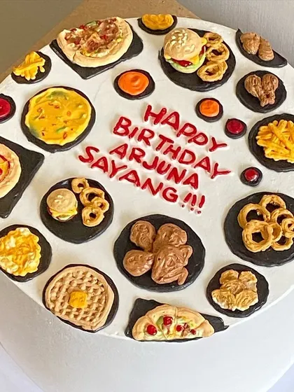 A fast-food lover's dream cake, covered in edible pizza, burgers, onion rings, and waffles.