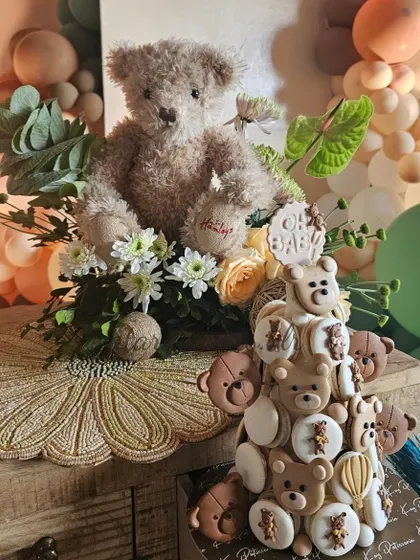 A tower of teddy bear-themed macarons and a floral centerpiece from a baby shower. This shows how I coordinate with vendors to ensure even the desserts match the theme perfectly.