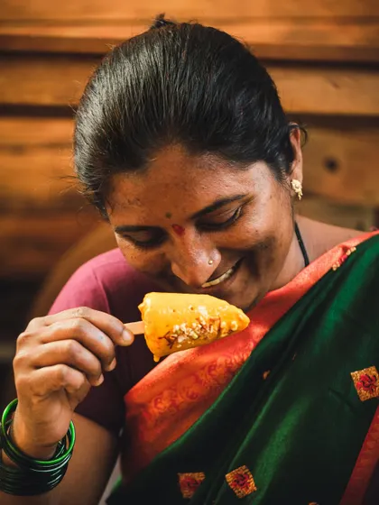 A woman from the local community enjoying a mango popsicle, her smile radiating pure happiness. This lifestyle shot connects the final product back to its roots.