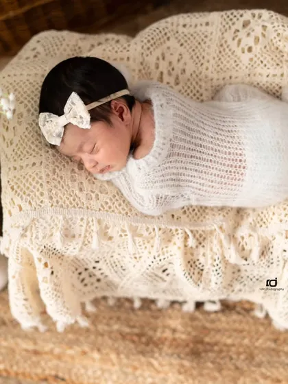 This little doll is resting on a tiny lace-covered bed. The delicate textures and her sweet sleeping pose make for such a precious newborn photograph.