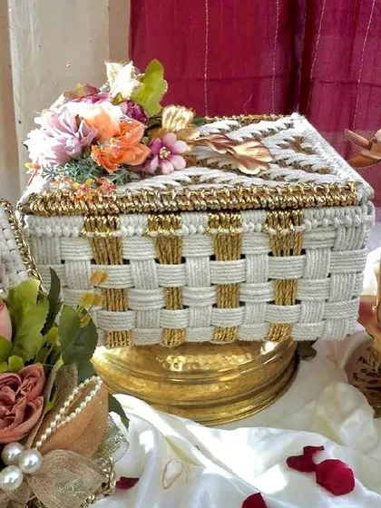 This is the lidded version of our popular woven Diwali hamper from the Rang & Noor collection. The floral arrangement on top adds a touch of elegance, making the unboxing experience even more special.