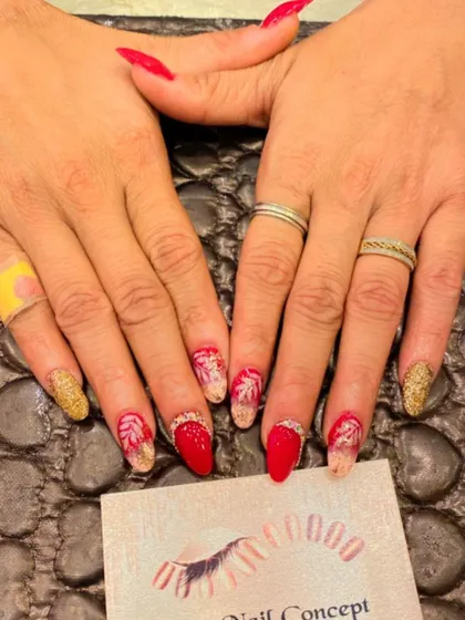 A festive and fiery design with red and gold nails. The art includes gold glitter, red polish, and accent nails with a delicate leaf pattern.