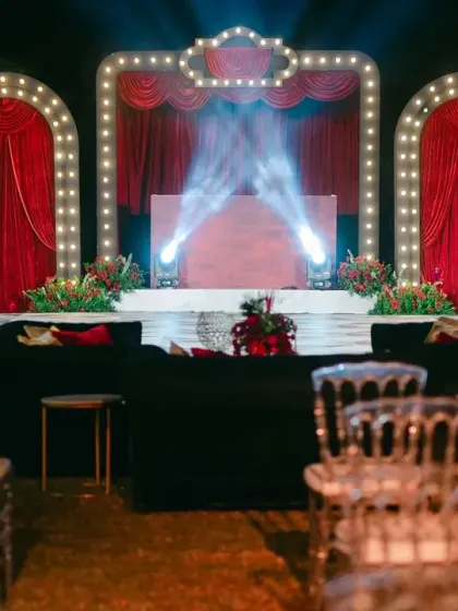The stage is set for a show-stopping performance. With dramatic lighting and a classic red curtain backdrop, this Broadway-themed Sangeet stage was the perfect setting for the couple's first dance.