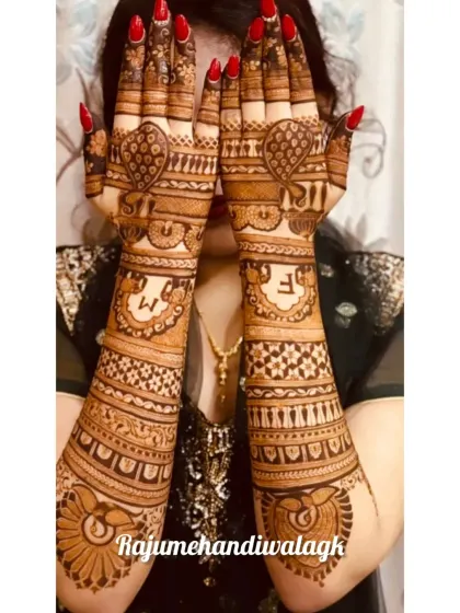A beautiful example of a full-coverage design, where the client is showing off the rich henna stain. The design includes peacocks and a space for the couple's initials.
