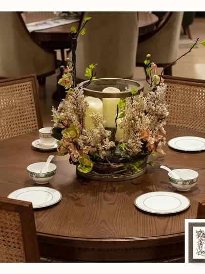 This handcrafted centerpiece combines artificial florals with the soft glow of candlelight. The rustic twigs and natural textures set the perfect mood for an elegant and cozy gathering around the dining table.