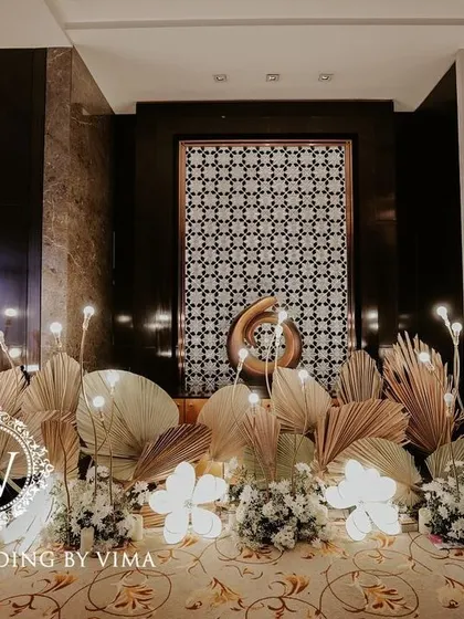A classic and elegant reception setup symbolizing everlasting love. The stage features a modern, minimalist backdrop with custom monograms, floral arrangements, and soft lighting.
