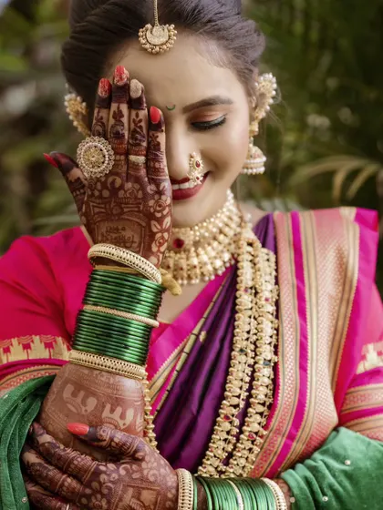 A playful and shy pose, with the bride partially covering her face with her henna-adorned hand. This shot captures her personality and the intricate details of her bridal look.