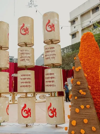 A unique installation of stacked lanterns with 'Om' symbols and cones wrapped in marigold garlands, blending spiritual and decorative elements.