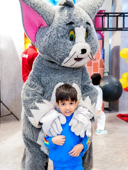The birthday boy gets a hug from Tom, the cat from Tom & Jerry, showing the joy our character mascots bring to children.