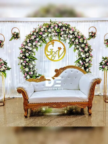 A clean and elegant engagement stage with a semi-circular floral arch. I used white and pink flowers with gold accents and tall floral stands to create a light, airy, and sophisticated atmosphere.