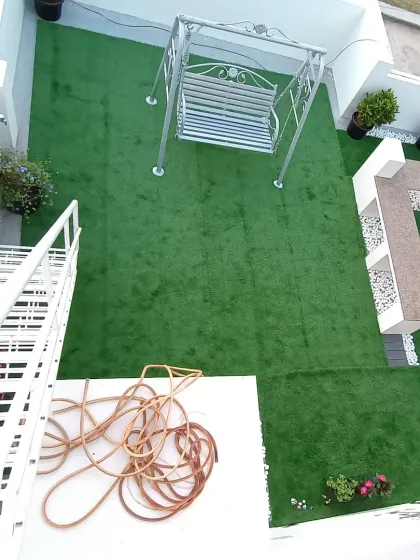 An overhead view looking down from the stairs onto the completed rooftop lawn, showing the layout of the swing and seating area.
