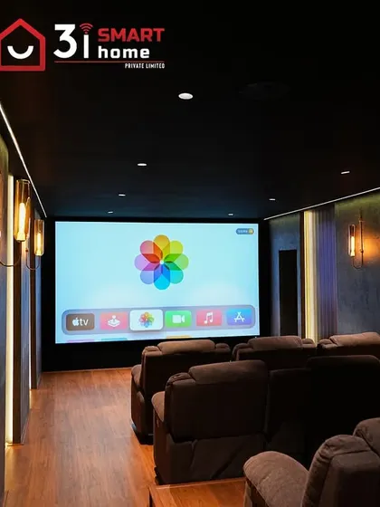 The warm glow from the wall sconces and vertical LED strips beautifully illuminates the textured walls and wood flooring in this Chennai theater.